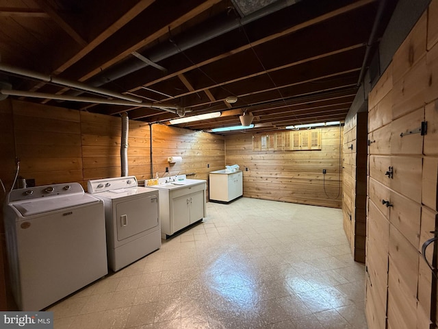 washroom featuring cabinets, washing machine and clothes dryer, and wood walls