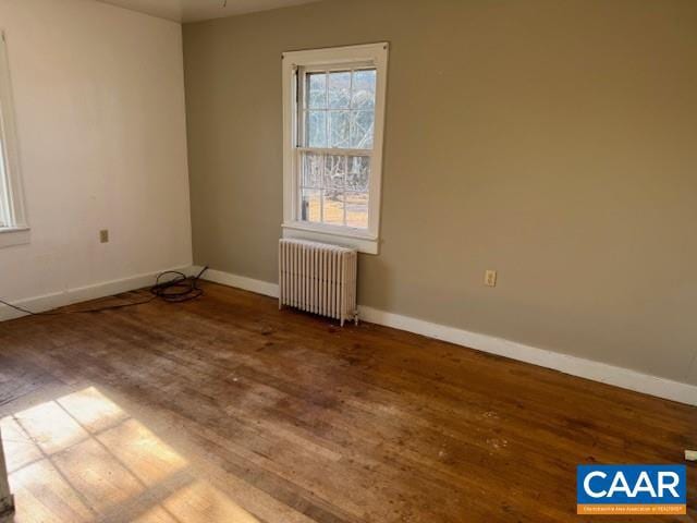 unfurnished room featuring radiator heating unit and hardwood / wood-style floors