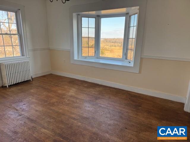 spare room with radiator, dark hardwood / wood-style floors, and a chandelier