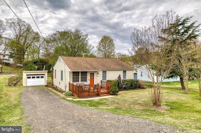 view of front facade with an outbuilding, a wooden deck, roof with shingles, a front lawn, and driveway