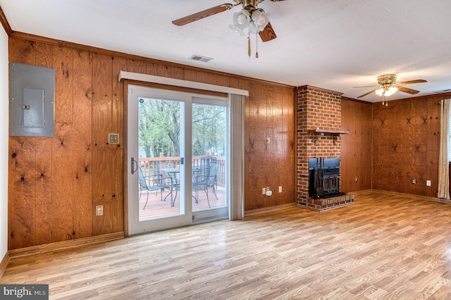 unfurnished living room featuring wooden walls, ceiling fan, and electric panel