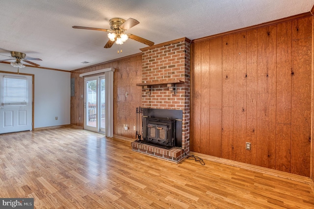 unfurnished living room with wooden walls, ceiling fan, wood finished floors, and a textured ceiling
