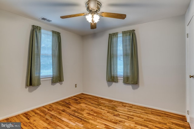 spare room with visible vents, baseboards, a ceiling fan, and wood finished floors