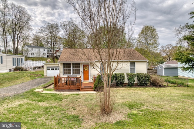 view of front of home with a shingled roof, a front yard, fence, and an outdoor structure