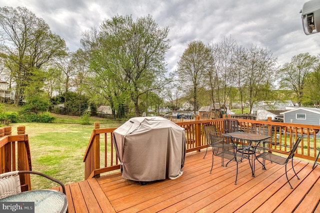 wooden terrace featuring grilling area, fence, outdoor dining area, and a lawn