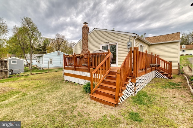 rear view of property with a wooden deck, fence, a lawn, and a chimney