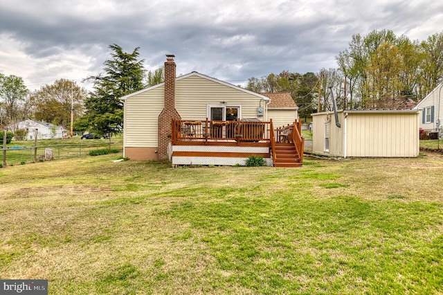 rear view of house with an outdoor structure, a storage shed, a yard, a deck, and fence