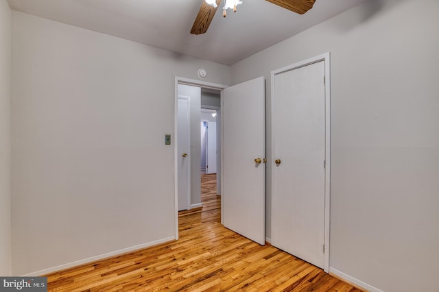 unfurnished bedroom with a closet, baseboards, light wood finished floors, and a ceiling fan