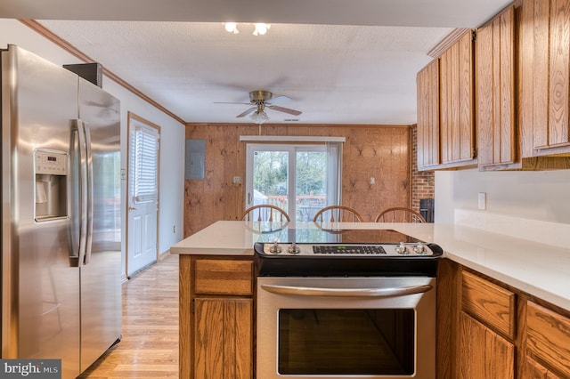 kitchen featuring stainless steel appliances, brown cabinets, light countertops, and ceiling fan