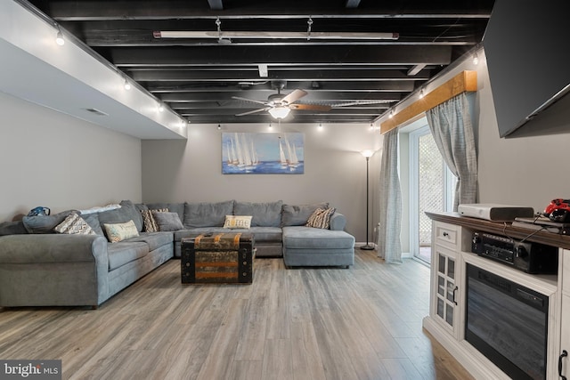 living room featuring hardwood / wood-style flooring, rail lighting, ceiling fan, and beamed ceiling