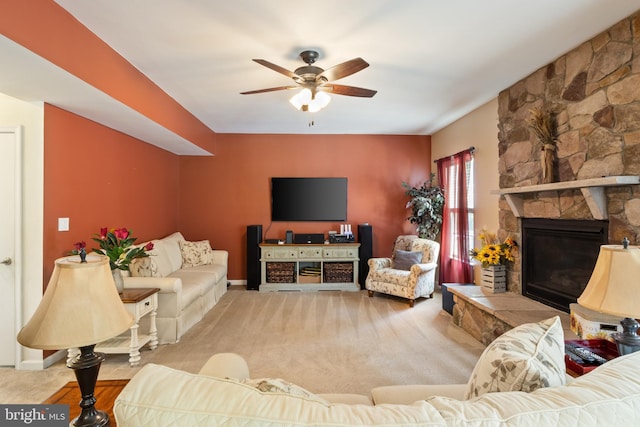 carpeted living room with ceiling fan and a fireplace