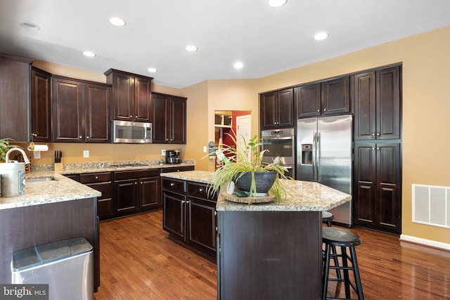 kitchen with dark hardwood / wood-style flooring, sink, stainless steel appliances, and a center island