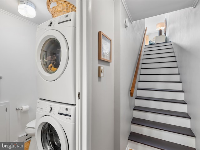 laundry area with stacked washing maching and dryer and crown molding