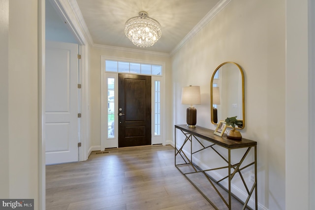 foyer entrance with a notable chandelier, ornamental molding, and light hardwood / wood-style floors