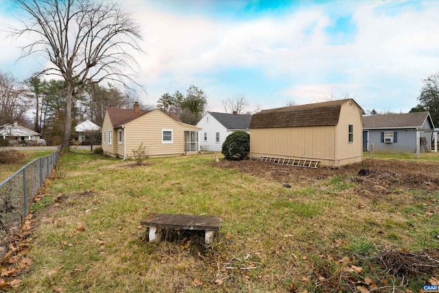 back of property featuring a storage unit and a lawn