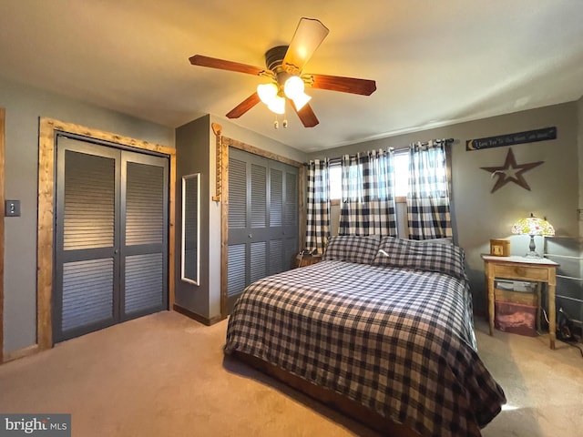 carpeted bedroom featuring ceiling fan and multiple closets