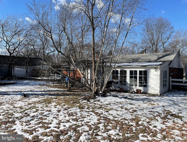 snow covered rear of property with a trampoline