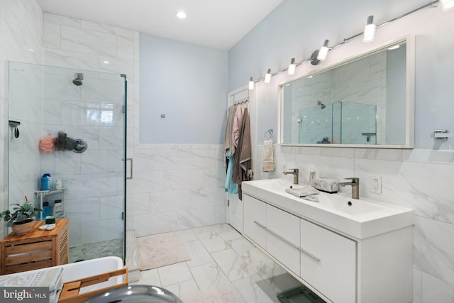 bathroom featuring a shower with shower door, tile walls, and vanity