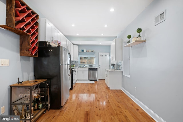 kitchen with light hardwood / wood-style flooring, tasteful backsplash, stainless steel appliances, sink, and white cabinetry