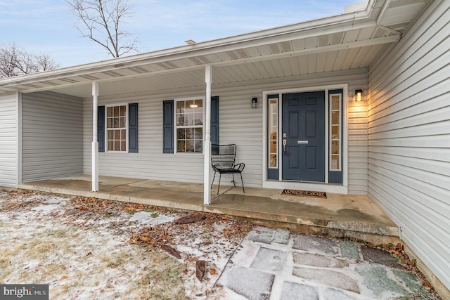 snow covered property entrance with covered porch