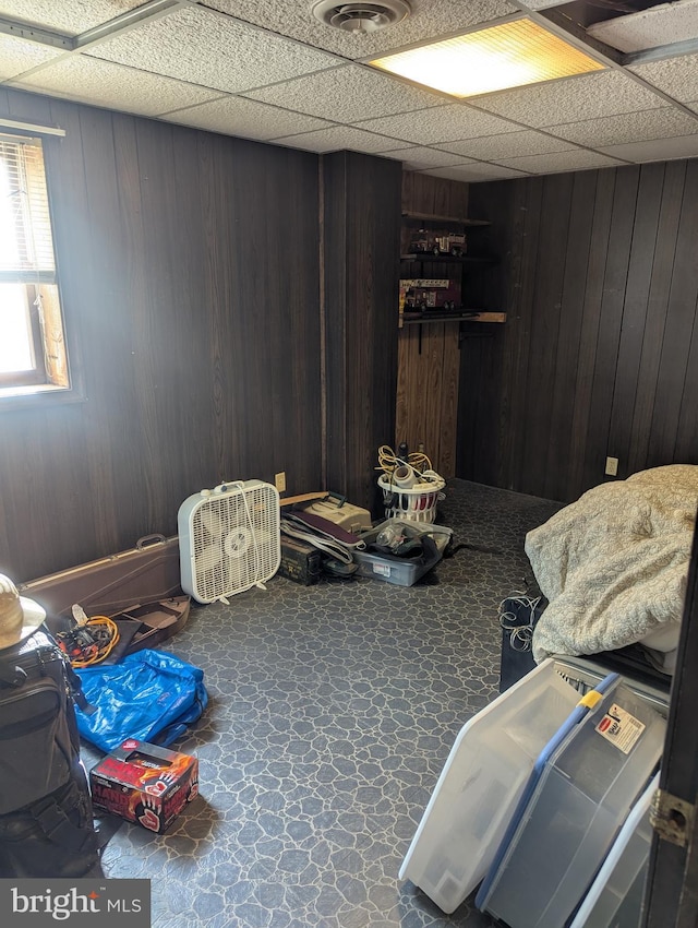 misc room featuring a drop ceiling and wood walls