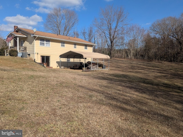 rear view of house featuring a carport, central AC unit, and a lawn