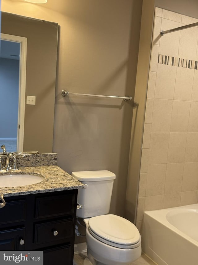 full bathroom with tiled shower / bath, vanity, and toilet