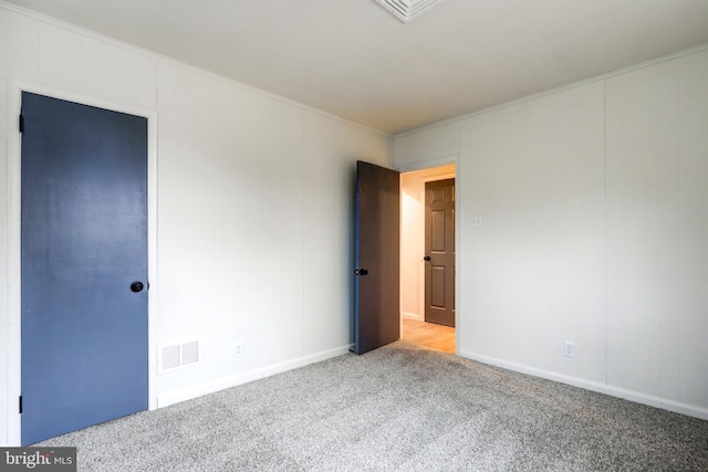 carpeted spare room featuring crown molding