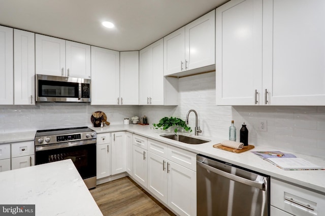 kitchen featuring white cabinetry, sink, wood-type flooring, and stainless steel appliances