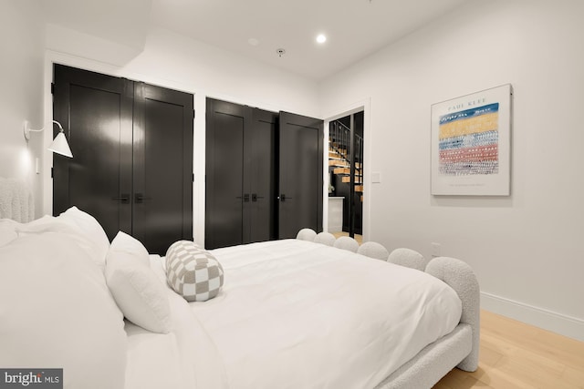 bedroom with multiple closets and light hardwood / wood-style flooring