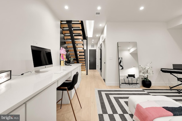 office with built in desk and light wood-type flooring