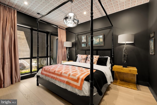 bedroom with brick ceiling and light wood-type flooring