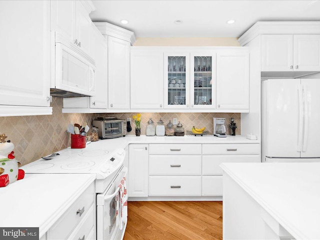 kitchen with white appliances, white cabinetry, light hardwood / wood-style flooring, and tasteful backsplash