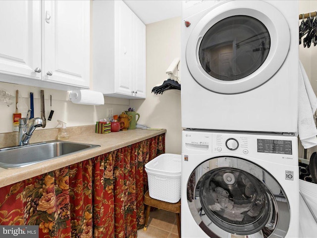 laundry area featuring sink, cabinets, stacked washer / dryer, and tile patterned floors