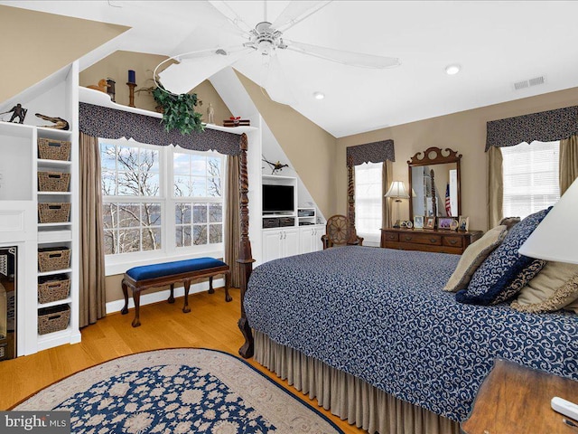 bedroom featuring light hardwood / wood-style floors, lofted ceiling, ceiling fan, and multiple windows