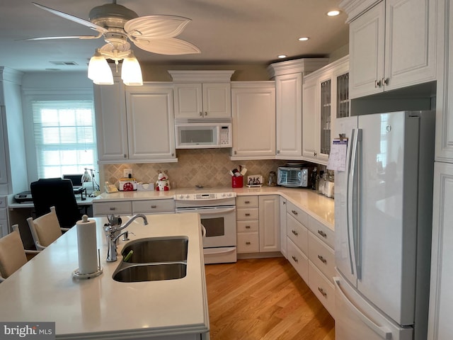 kitchen with white appliances, light hardwood / wood-style flooring, sink, white cabinets, and decorative backsplash