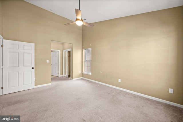 unfurnished bedroom with ceiling fan, light colored carpet, and a high ceiling