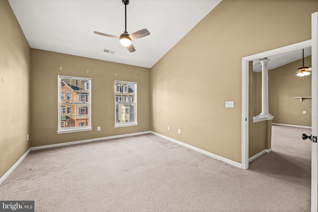 spare room featuring light carpet, vaulted ceiling, ceiling fan, and ornate columns