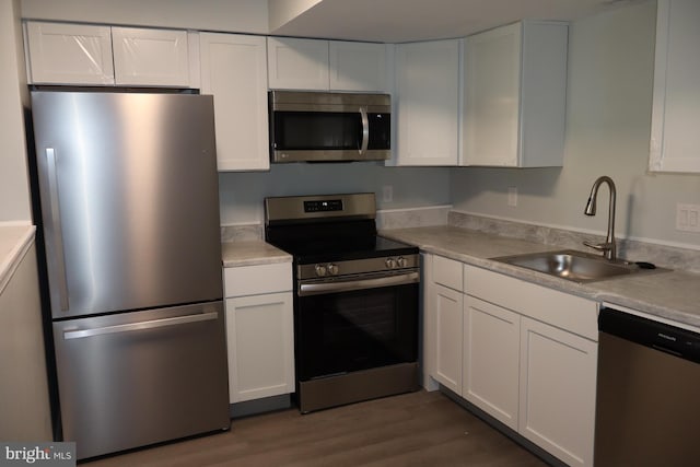 kitchen with sink, dark wood-type flooring, stainless steel appliances, and white cabinets