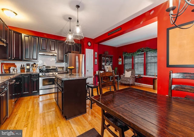 kitchen featuring appliances with stainless steel finishes, stone countertops, pendant lighting, sink, and a center island