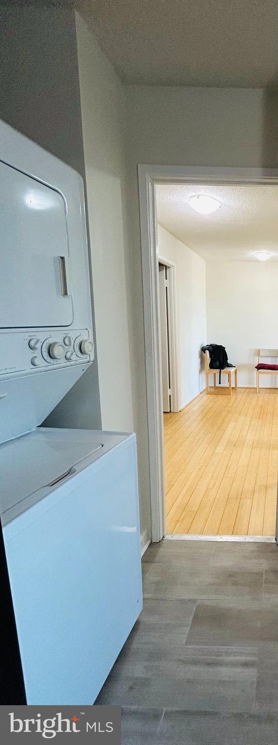 washroom featuring hardwood / wood-style flooring and stacked washer and clothes dryer