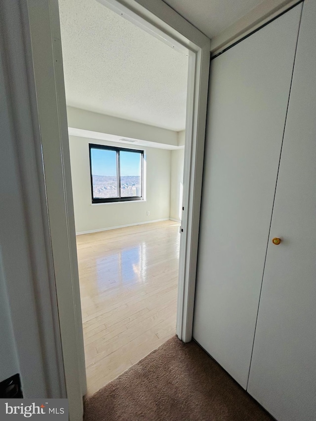 corridor featuring hardwood / wood-style flooring and a textured ceiling