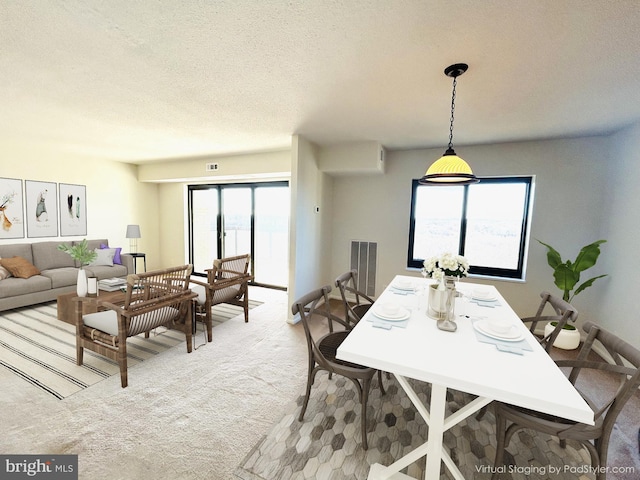 carpeted dining space featuring a textured ceiling