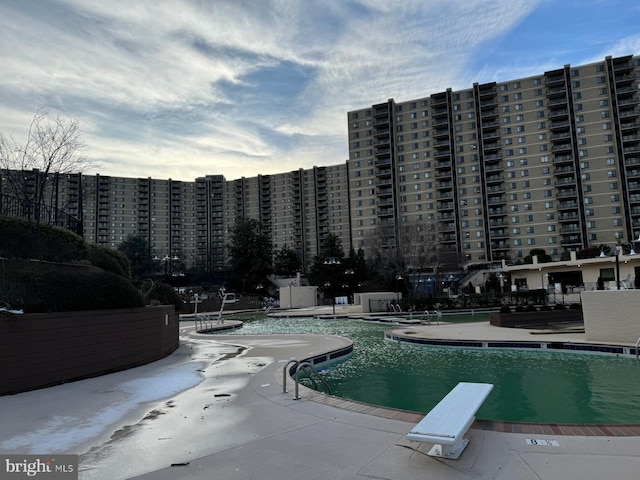 view of pool featuring a diving board and a patio area