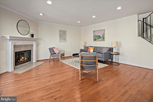 living room with a fireplace, ornamental molding, and light hardwood / wood-style flooring