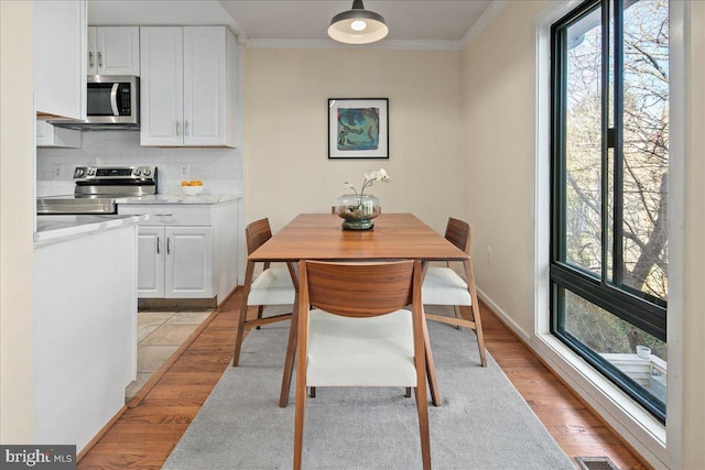 dining room featuring a wealth of natural light, crown molding, and light hardwood / wood-style flooring