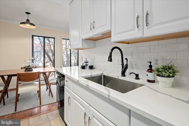 kitchen with sink, white cabinets, hanging light fixtures, ornamental molding, and decorative backsplash