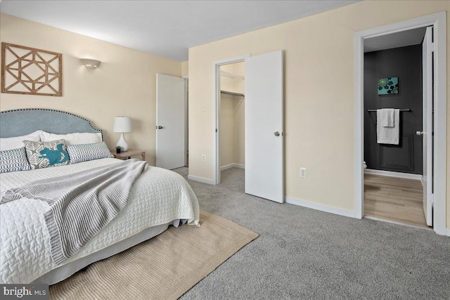 bedroom featuring a closet, ensuite bath, a spacious closet, and light colored carpet