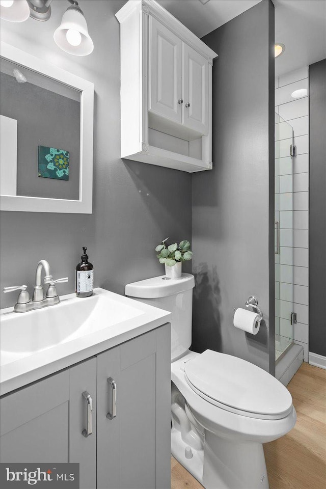 bathroom featuring toilet, a shower with door, hardwood / wood-style floors, and vanity