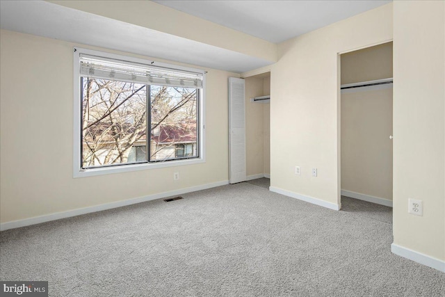 unfurnished bedroom featuring carpet and multiple closets